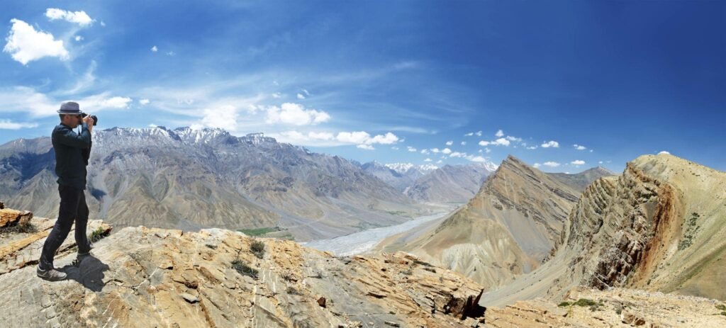 Traveller standing at a viewpoint surrounded by an expansive Himalayan mountain landscape